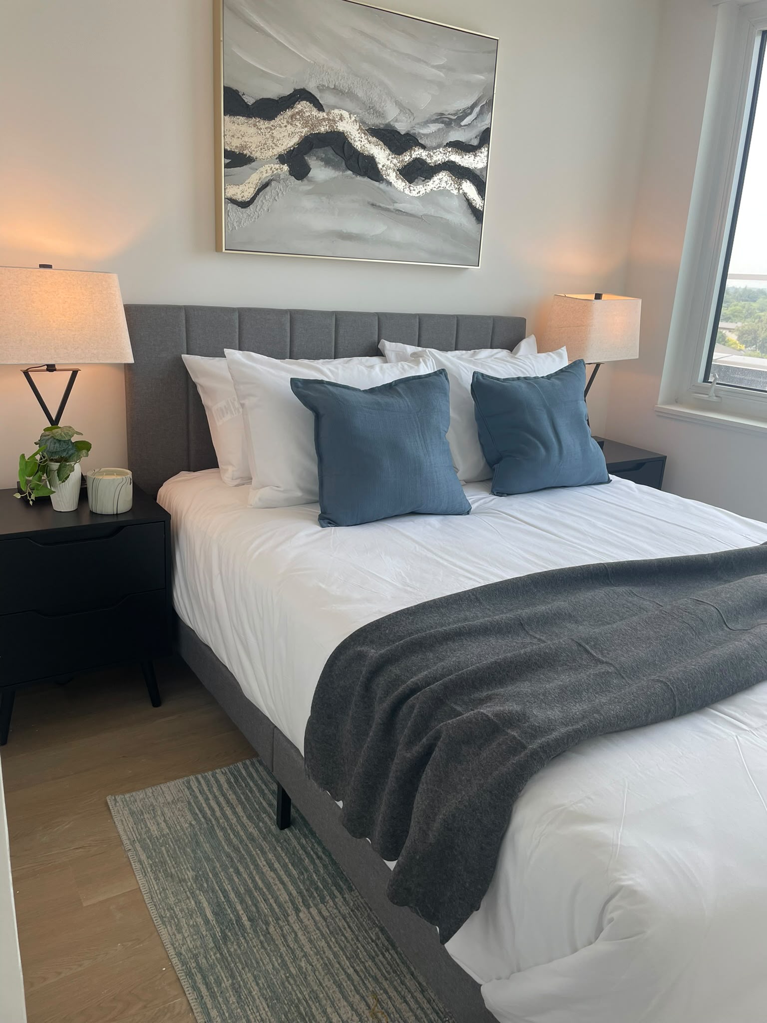 Finished bedroom with fresh white linens, blue pillows, bedside tables, and warm lamps