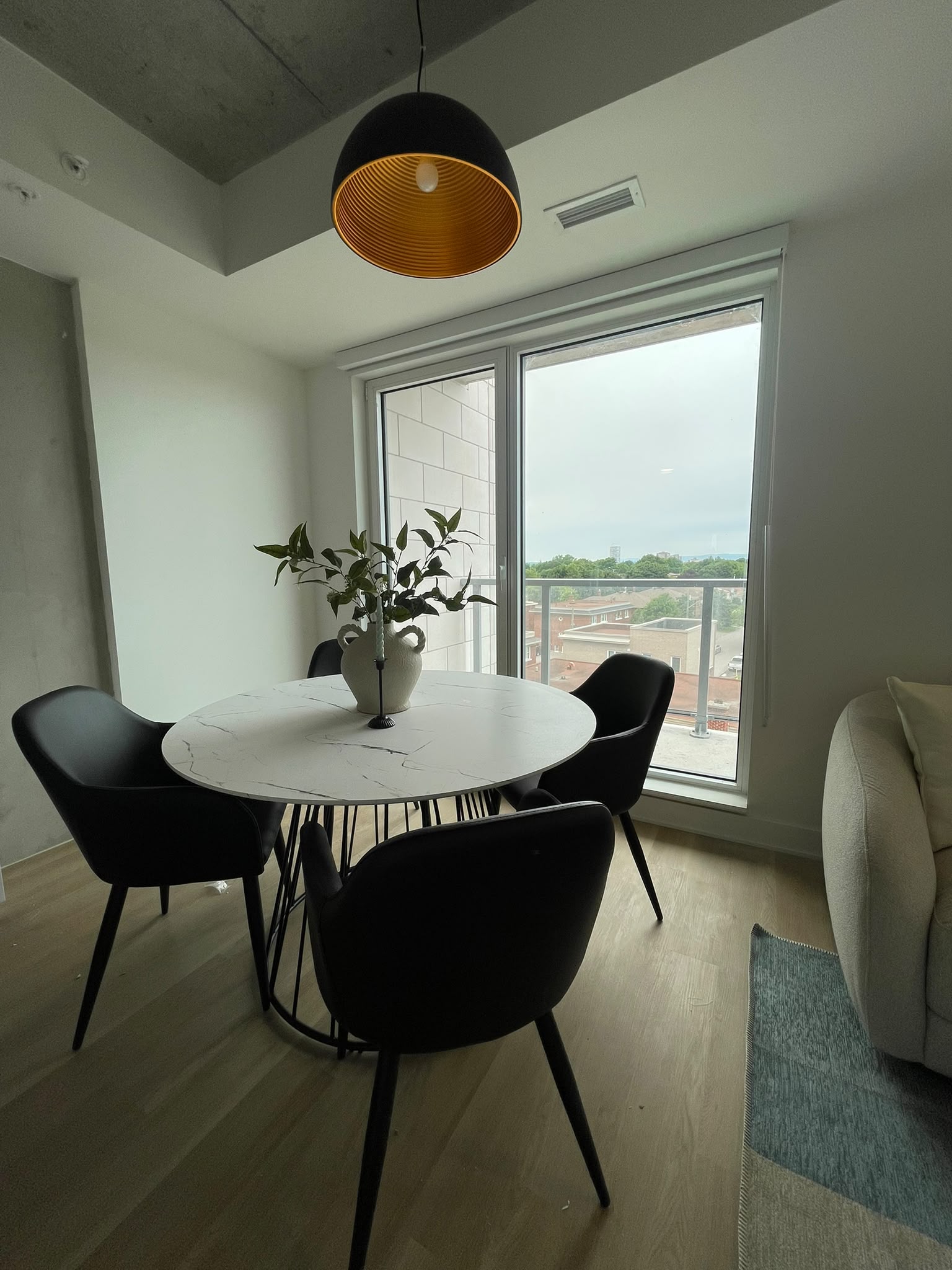 Dining table with four chairs beside large apartment windows